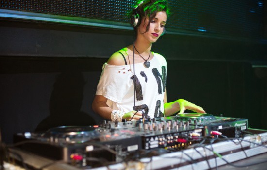 Female DJ creating electronic music in a club