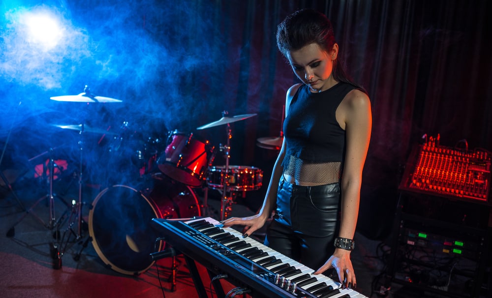 Young female keyboard player in empty rehearsal studio