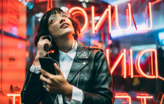 Hip woman listening to music podcast on her phone