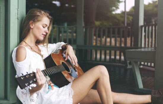 Songwriter playing guitar on her porch