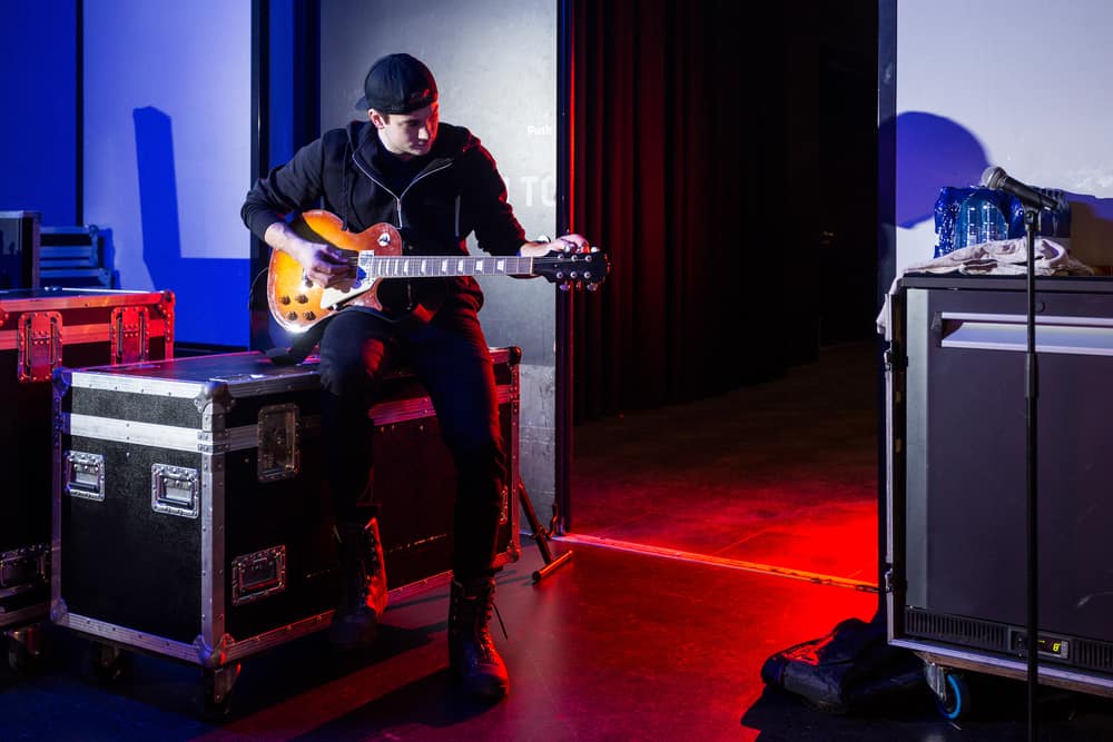 Backstage at concert venue with roadie tuning guitar