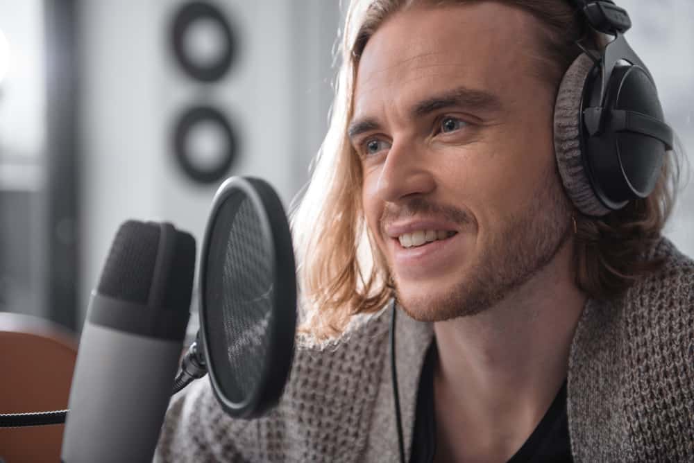 Cheap microphone and pop filter with male singer wearing headphones