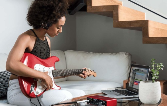 Female guitar player using audio interface to record guitar on her DAW