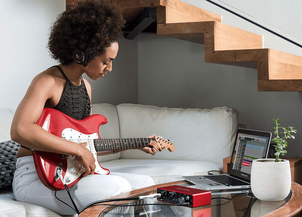 Female guitar player using audio interface to record guitar on her DAW