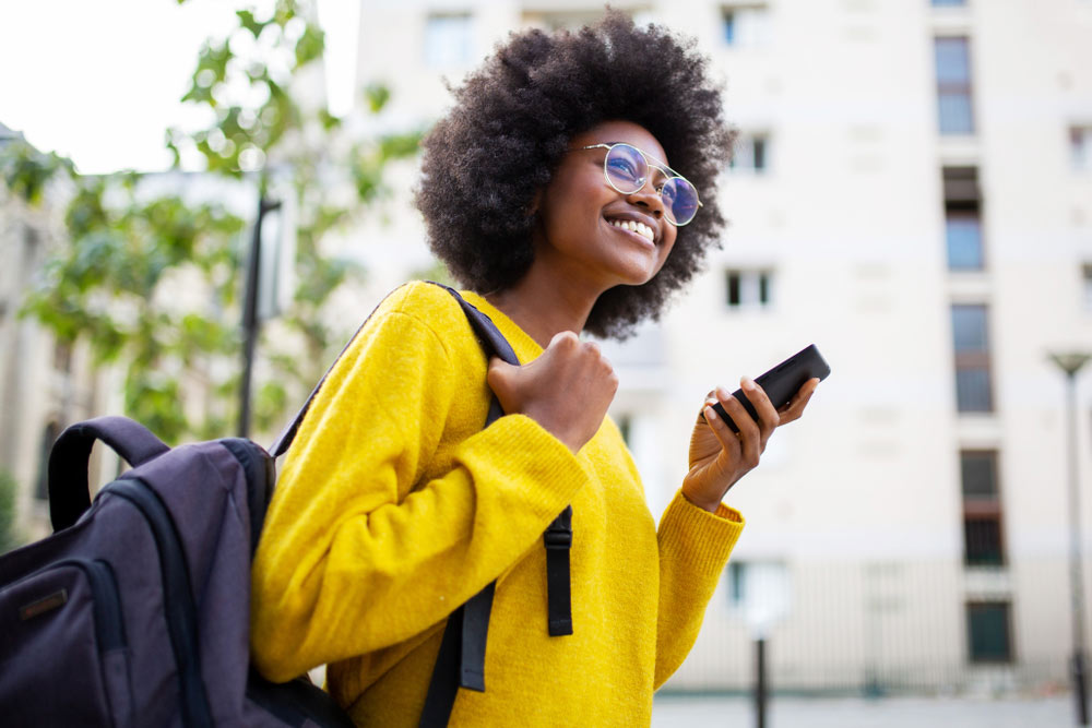 Young black woman with backpack walking alone through college campus