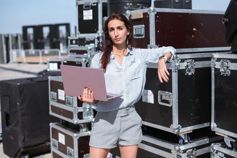 Music Manager with laptop standing outdoors near music gear