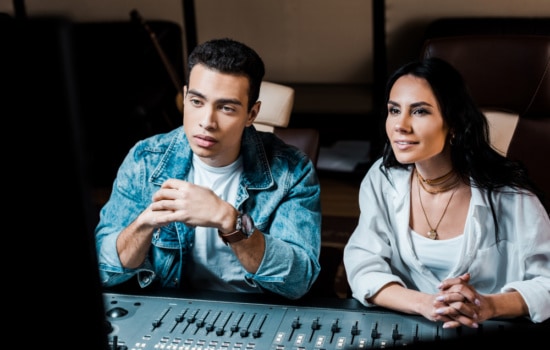 Sound engineers watching live recording behind mixing console