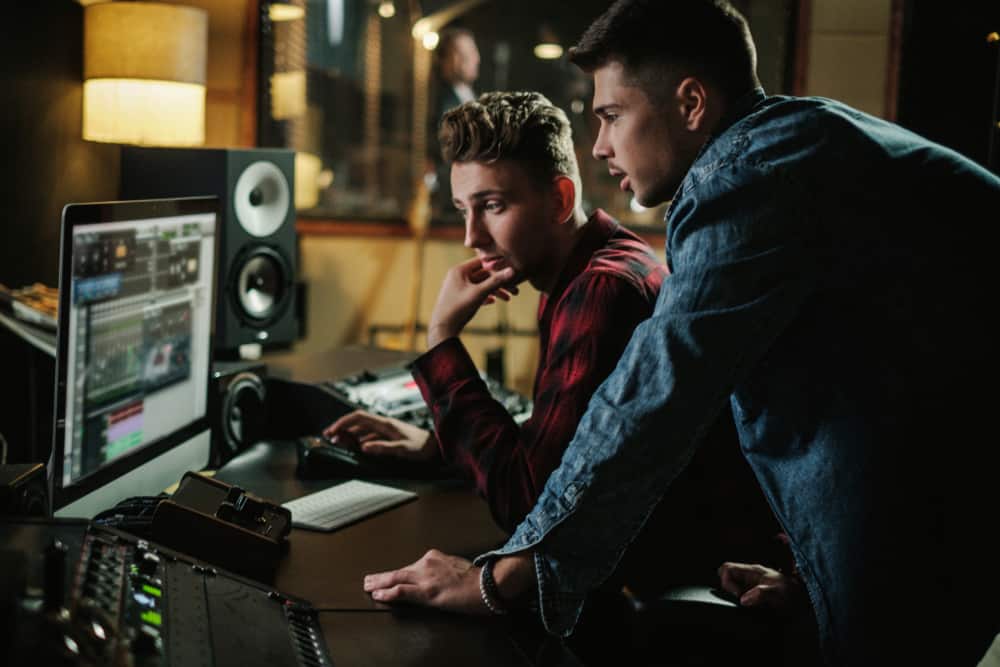 Two music producers using DAW in professional recording studio