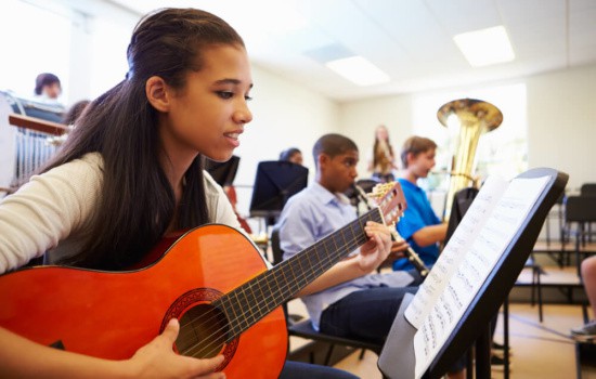 Female guitar student in music class at school