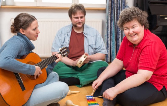 Music therapist playing guitar while her clients play other instruments