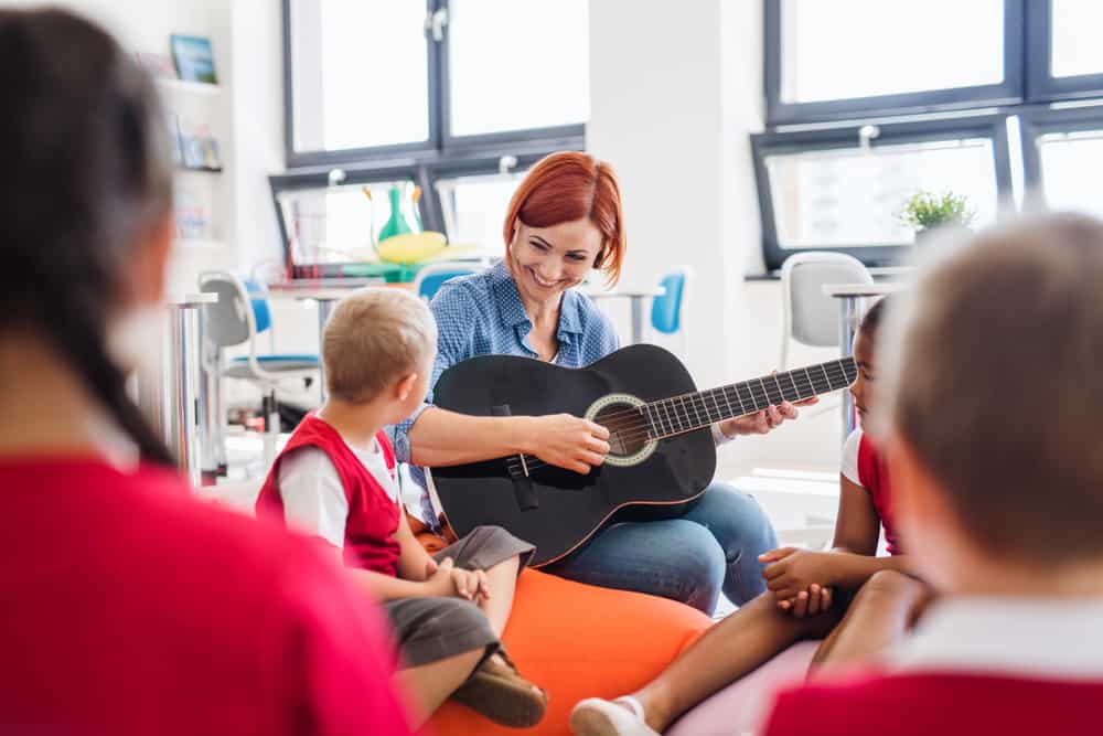 Music therapist playing guitar with small children