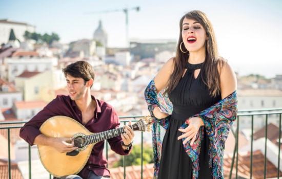 Female singer with male musician and stringed instrument performing outdoors