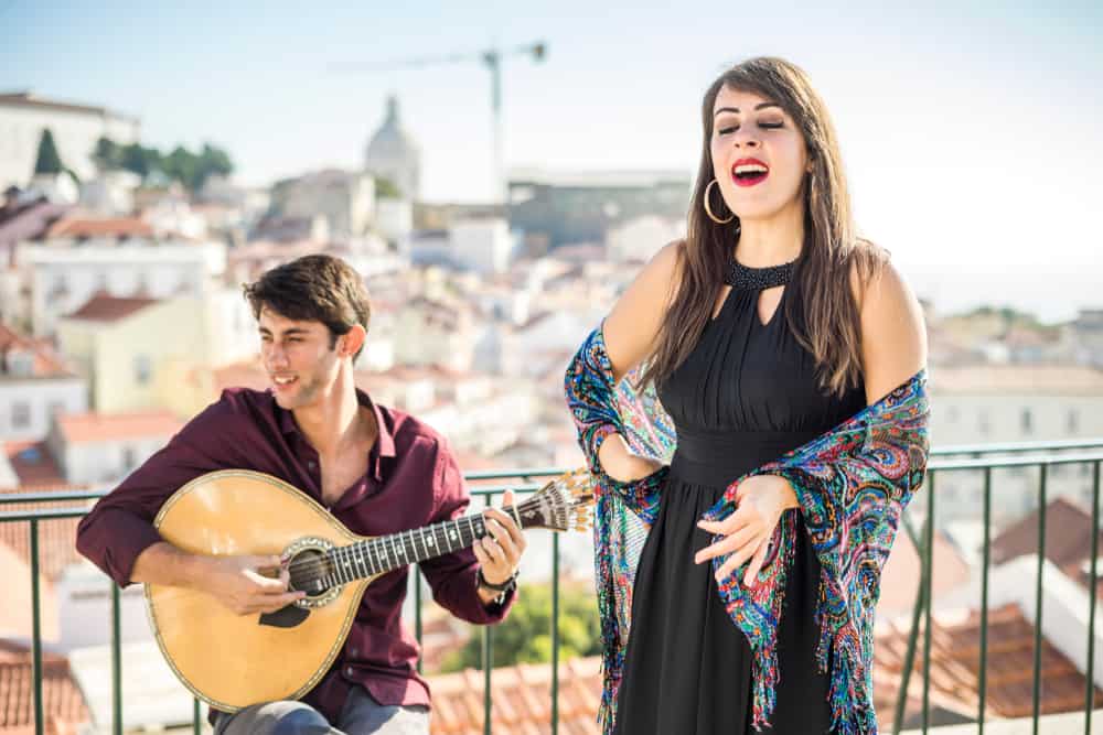 Female singer with male musician and stringed instrument performing outdoors