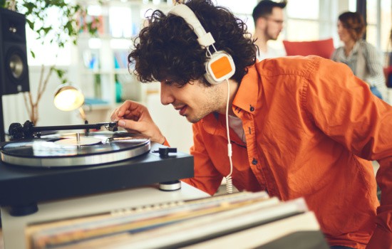 Young man in headphones putting the needle on a vinyl record