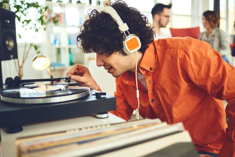 Young man in headphones putting the needle on a vinyl record