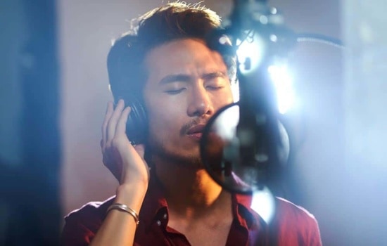 Singer with microphone and headphones in recording studio