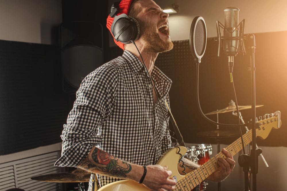 Male singer and guitarist performing in home recording studio