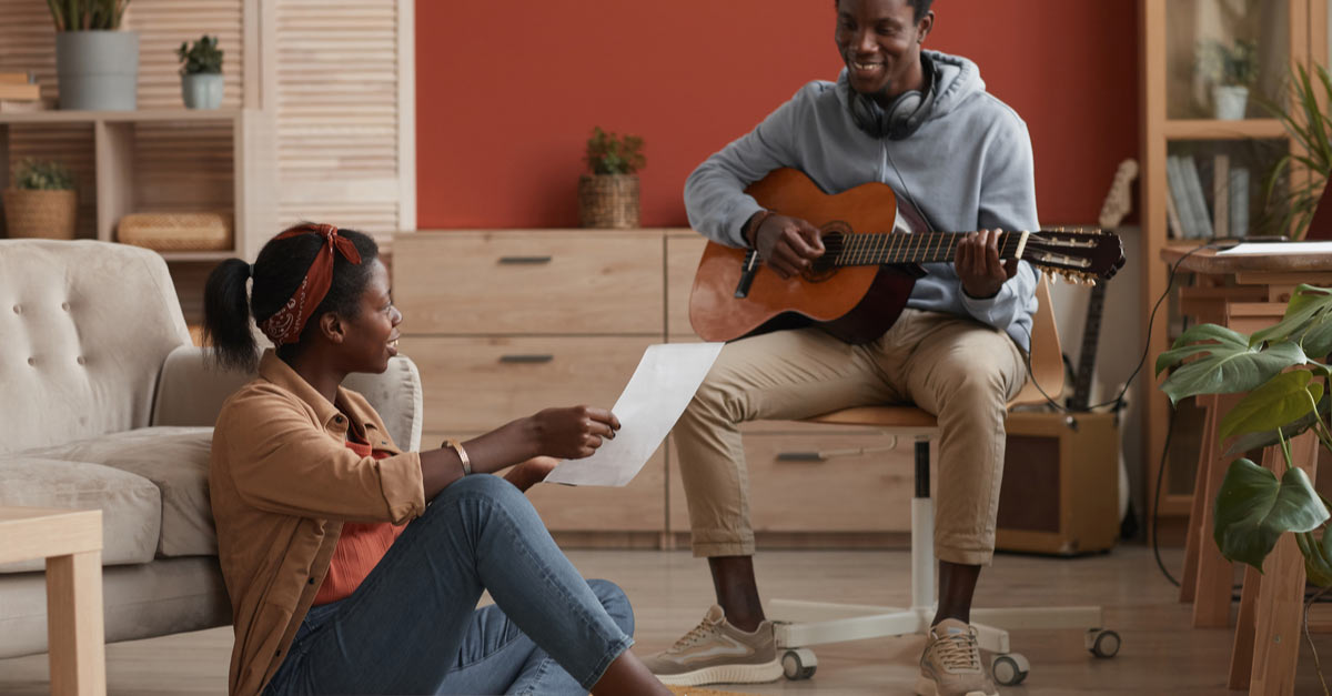 Male and female musicians write a song at home