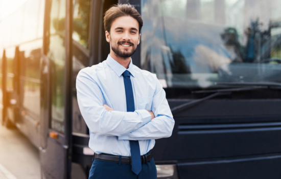 Male Tour Bus Driver standing outside a coach bus