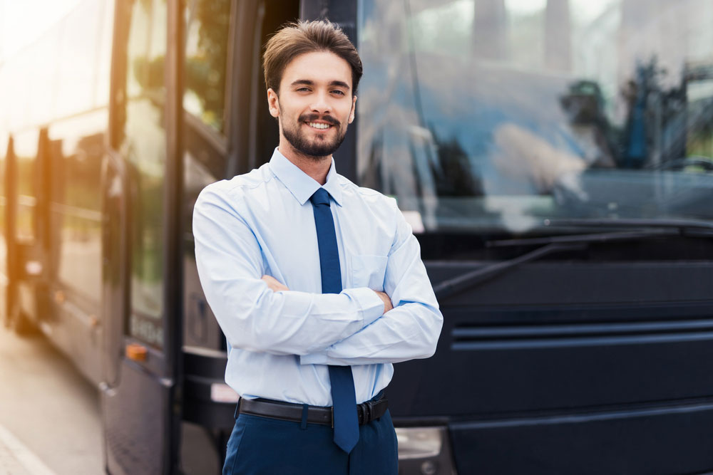 Male Tour Bus Driver standing outside a coach bus