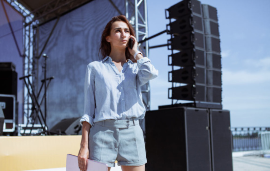 Female tour manager standing in front of large, empty concert stage