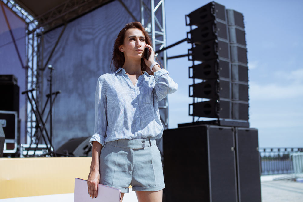 Female tour manager standing in front of large, empty concert stage