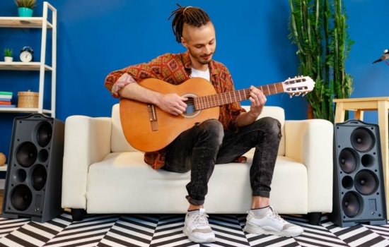 Young man learns music theory on his guitar at home