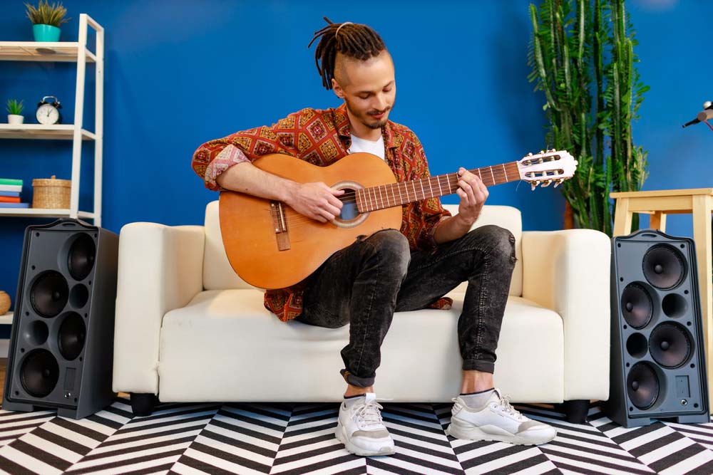 Young man learns music theory on his guitar at home