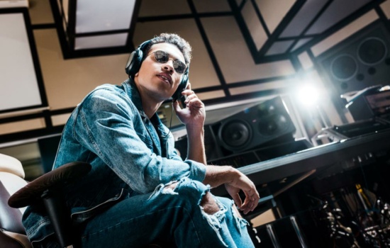 Young male producer listening to music on mixing headphones