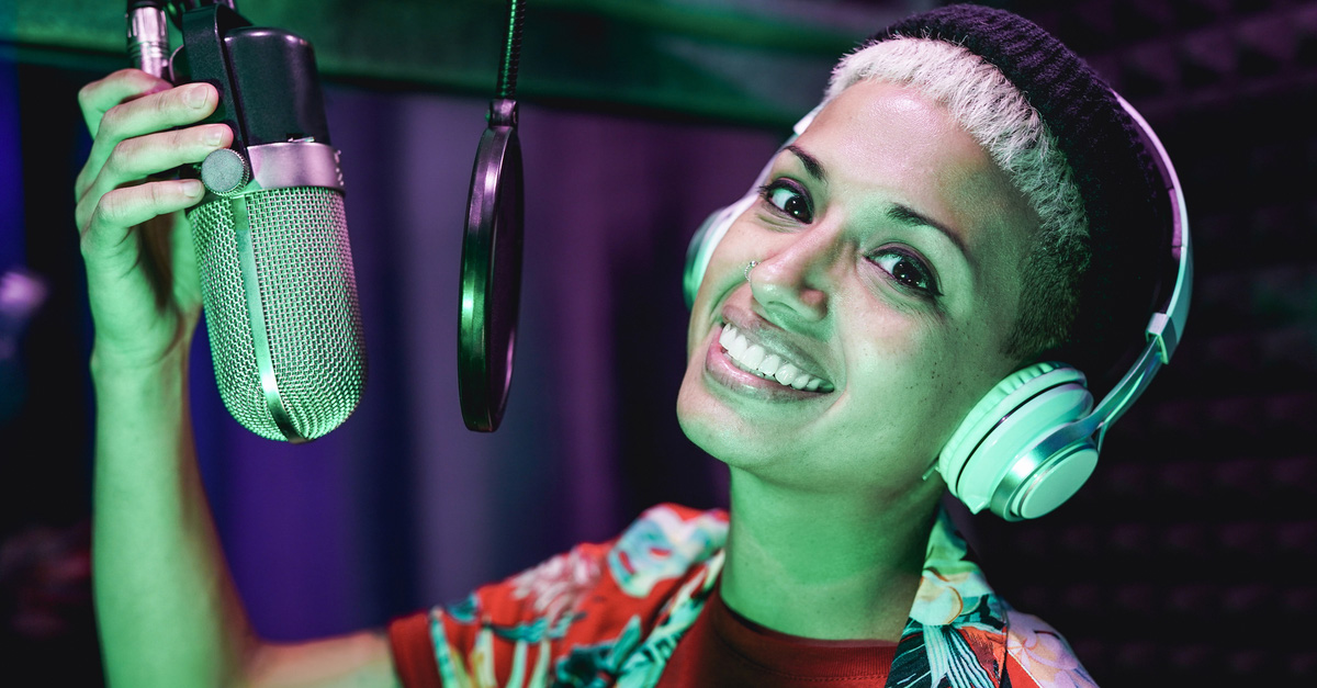Young bi-racial female singer practicing how to sing in recording studio