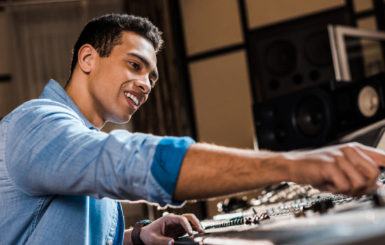 Young black male producer using soundboard at a music production school