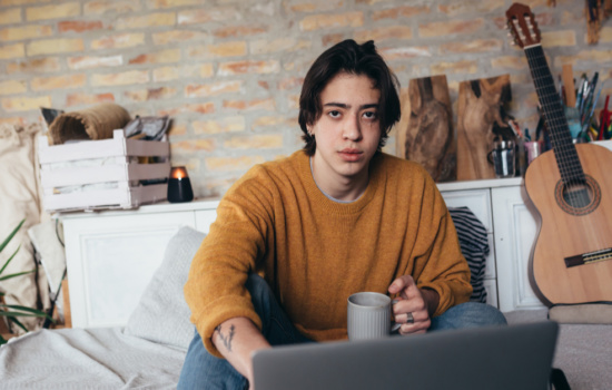 Online music school student at home with guitar and laptop