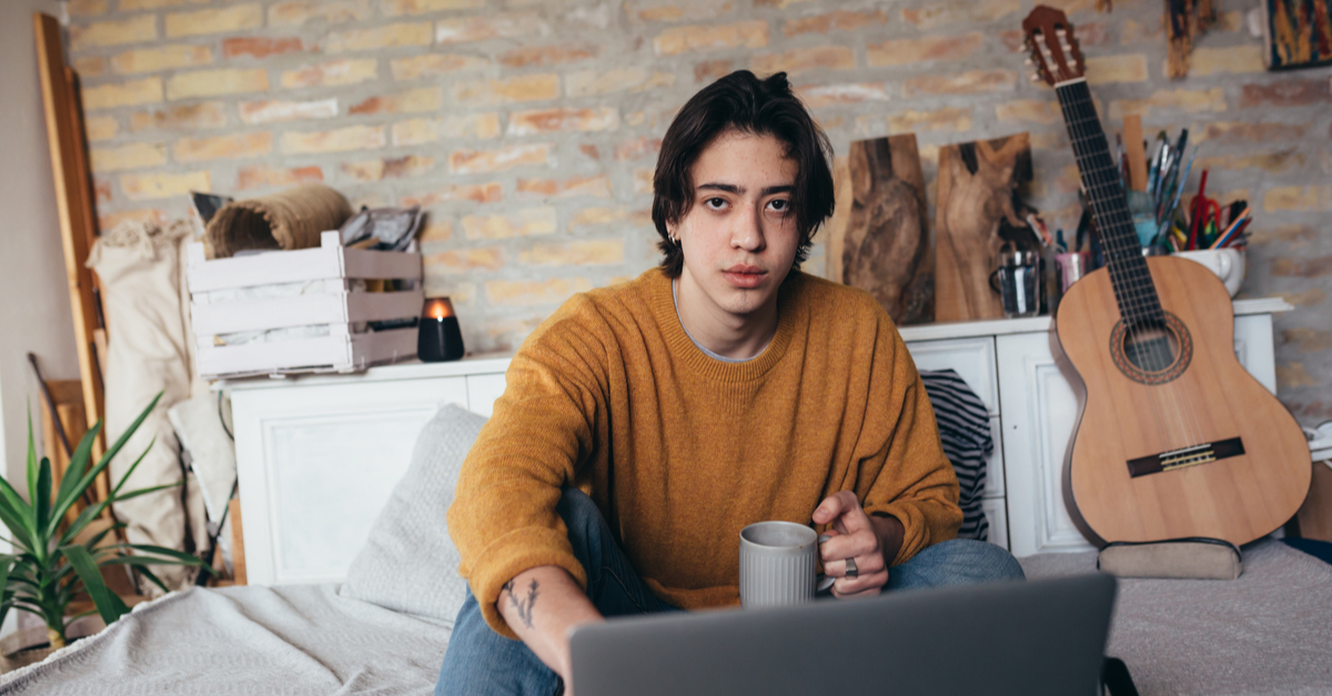 Online music school student at home with guitar and laptop