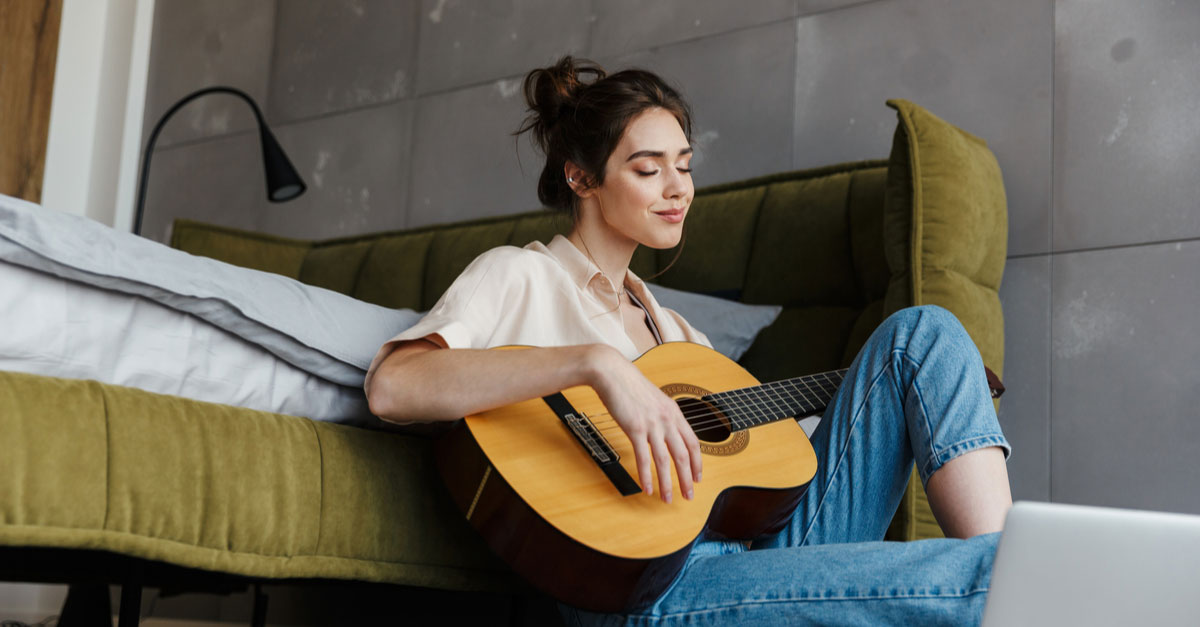 Woman playing guitar in her room