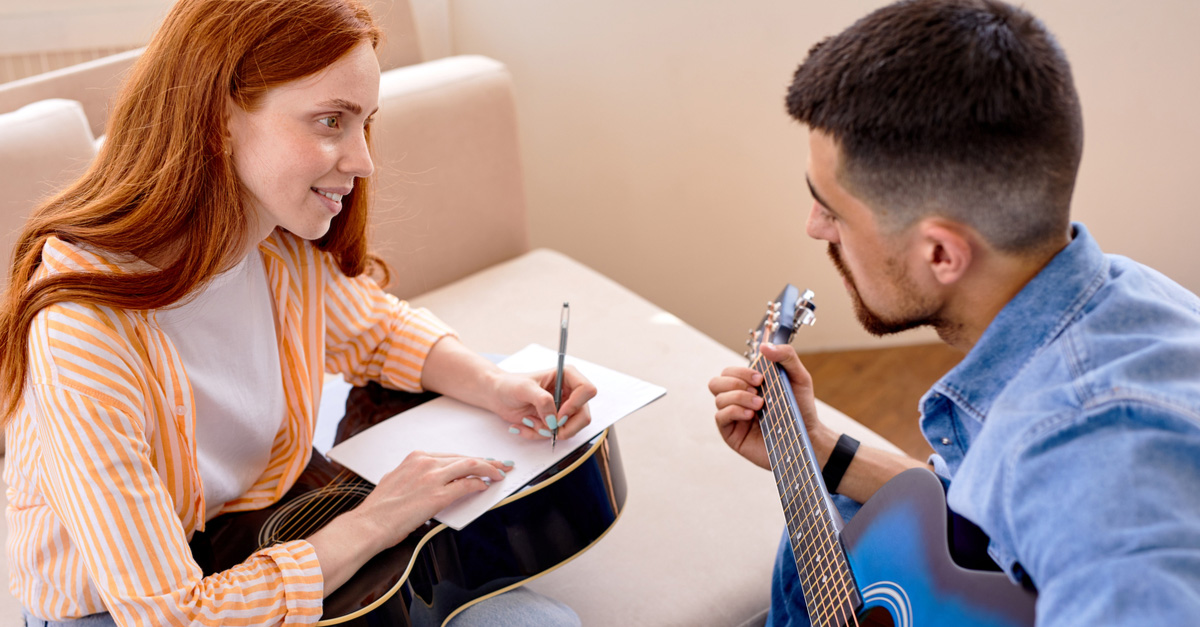 Male and female musicians sharing songwriting tips at home