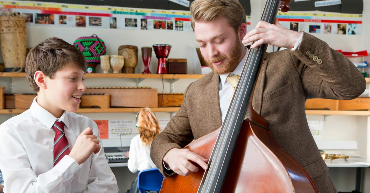 Music Teacher showing bass to young male music student