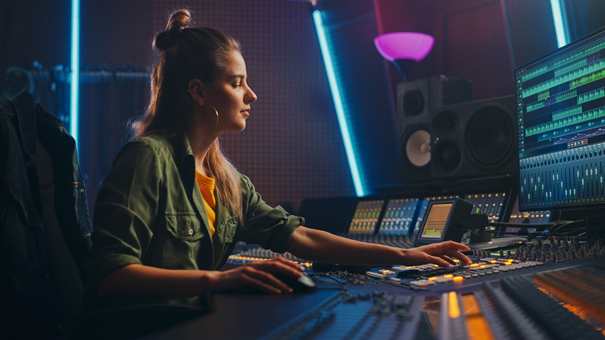A woman sits in a studio producing music.