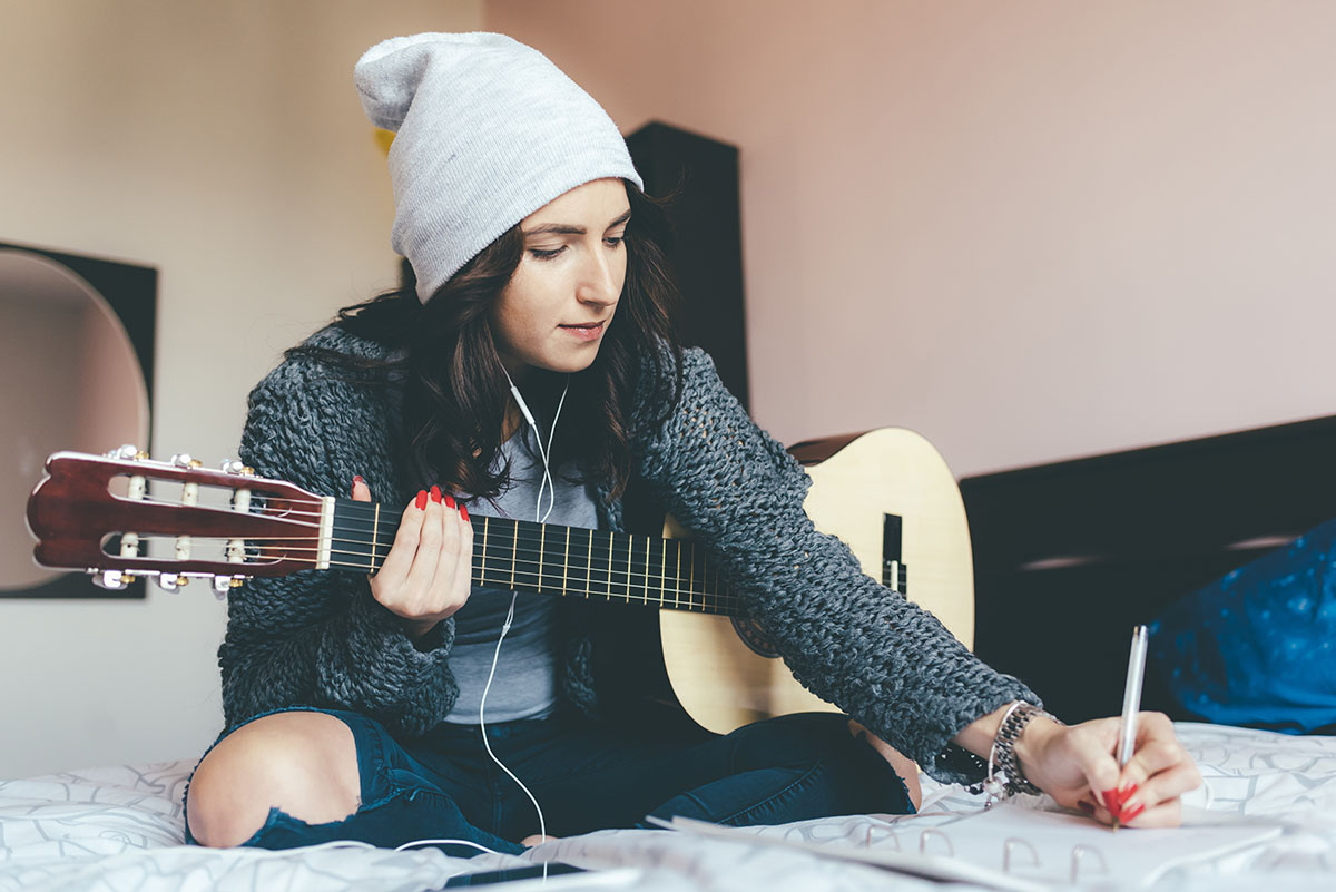 Woman sits on her bed and writes a song.